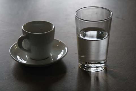 eine Espressotasse und ein Glas Wasser