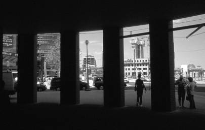 Vordergrund dunkel, hinten blick auf Potsdamer und unvollendeten Leipziger Platz, einige Passanten zwischen den Säulen des Ausgangsbereichs